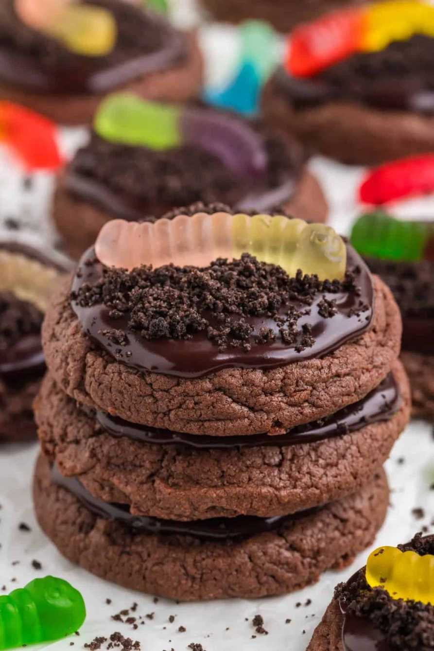 Chocolate cookies topped with crushed Oreo “dirt” and gummy worm decorations on a spooky plate